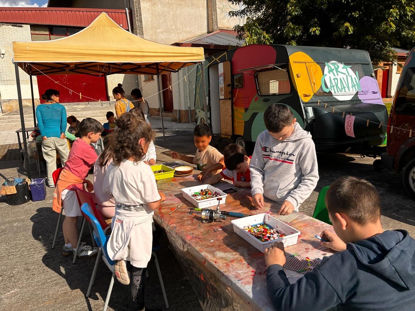 Taller Art Caravan · niños y niñas trabajando con la caravana al fondo